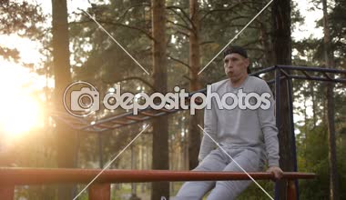 Genç adam akşam egzersiz yatay bar yapmak