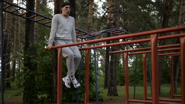 Young man doing exercise at the horizontal bar in the evening — Stock Video