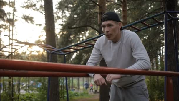 Retrato de un joven guapo con gorra en el bosque — Vídeo de stock