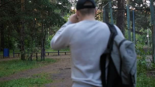 Один чоловік ходить в лісі з сумкою, вид ззаду — стокове відео
