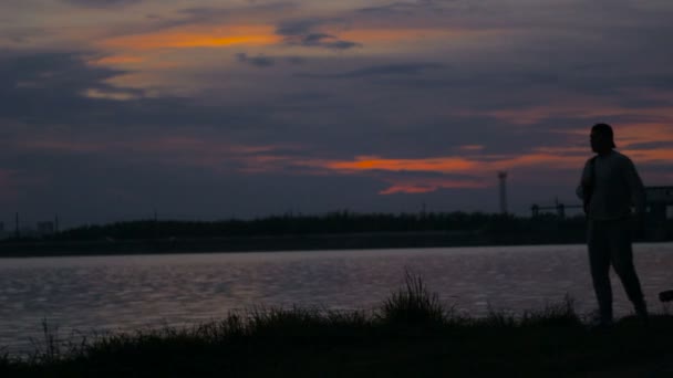 ビーチで散歩の男、停止し、再び深い日没時間を歩く — ストック動画