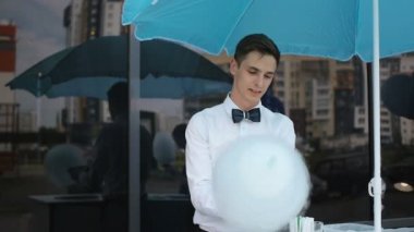 Özel bir makine üzerinde yapım pamuk şeker genç adam, balonlar arkasında papyon giyiyor