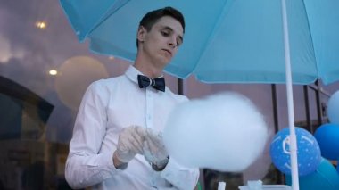 Özel bir makine üzerinde yapım pamuk şeker genç adam, balonlar arkasında papyon giyiyor