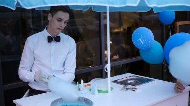 Özel bir makine üzerinde yapım pamuk şeker genç adam, balonlar arkasında papyon giyiyor