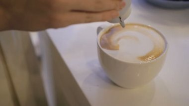 Barista çikolata sanat kahve latte beyaz bardakta çizer.