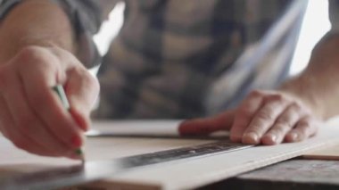 Marangoz bir cetvelin yardımıyla kurusıkı kalem işaretleri yapar.