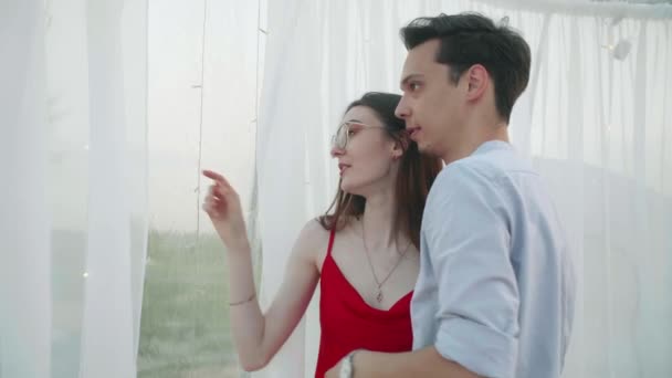 Young pretty couple stand near the panoramic window in the cafe — Wideo stockowe