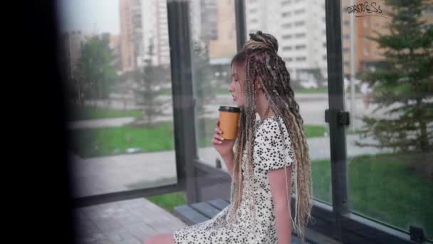 Menina com dreadlocks esperando por um ônibus e beber café — Vídeo de Stock