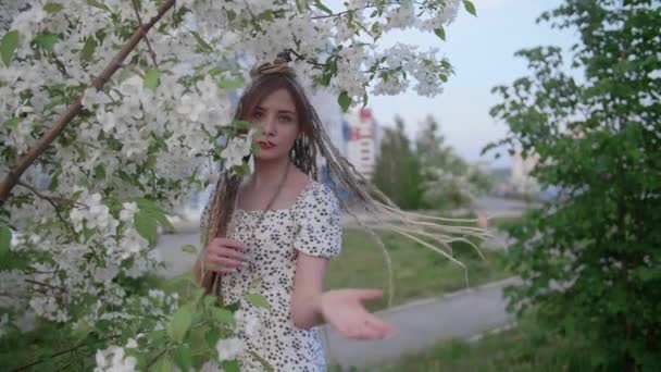 Una linda chica con rastas posa junto a un árbol con hojas — Vídeo de stock