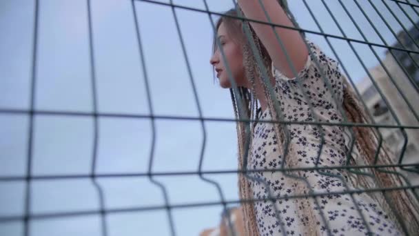 Chica joven con rastas posa en la valla — Vídeo de stock