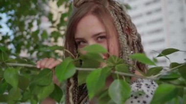 Rastalı şirin bir kız ağaçta yapraklarla poz veriyor.