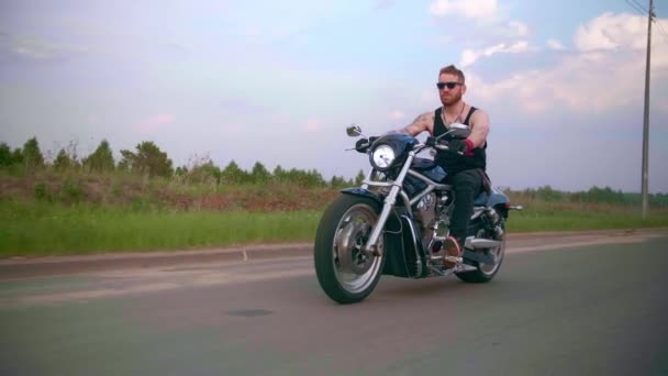 傍晚时分，带着纹身的时髦自行车手骑摩托车在乡间路上 — 图库视频影像