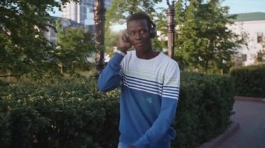 Zenci genç adam kulaklıkla müzik dinliyor.