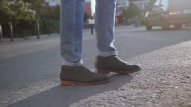 Gün batımında bir adam ayaklarının yakın planıyla sokakta yürür.