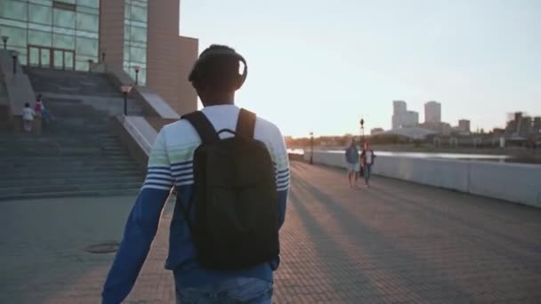 Zwarte student loopt rond in de stad bij zonsondergang hij is blij — Stockvideo