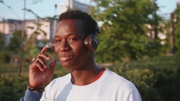 黒人青年はヘッドフォンで音楽を聴く — ストック動画