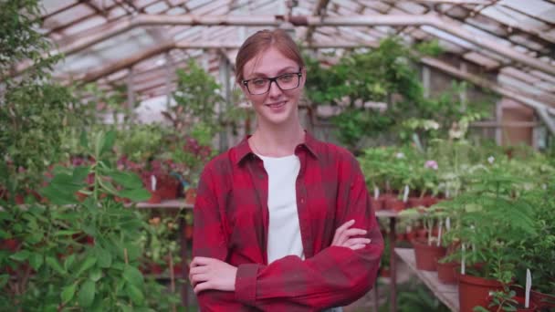 Retrato de um funcionário jovem de uma estufa na qual flores e fábricas se cultivam, o inspetor de menina — Vídeo de Stock