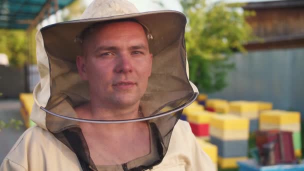Portret van een jonge eigenaar van een bijenstal waarop hij bijen en extracten honing kweekt — Stockvideo