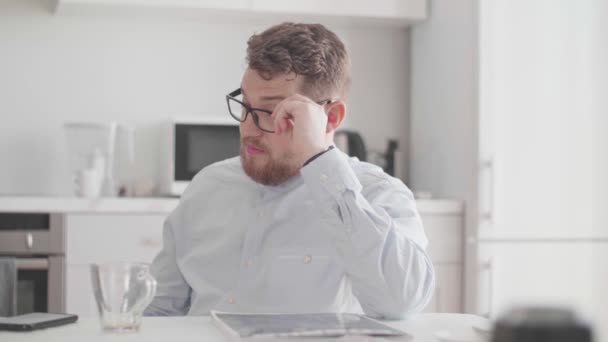 Ένας νεαρός άνδρας με γυαλιά και κομψά ελαφριά ρούχα επικοινωνεί με ένα σπιτικό πρωινό — Αρχείο Βίντεο