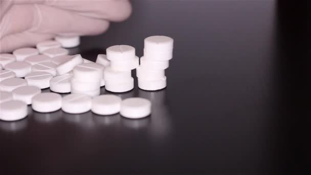 Белые таблетки разбросаны по столу — стоковое видео
