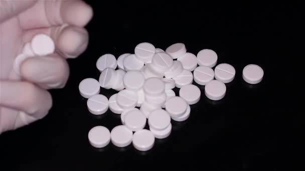 Белые таблетки разбросаны по столу — стоковое видео