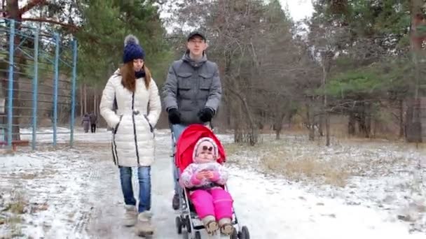 Молодая семья с ребенком гуляет по улице — стоковое видео