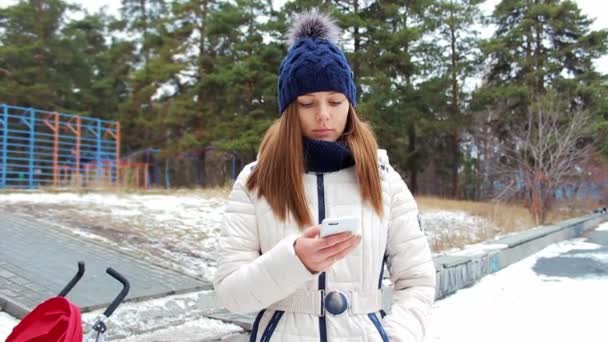 Bela jovem mãe com um smartphone — Vídeo de Stock