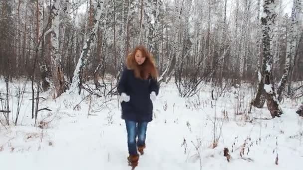 Девушка, гуляющая в зимнем лесу с телефоном — стоковое видео