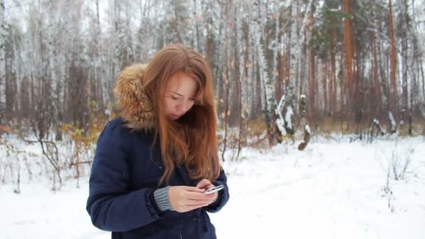 La chica caminando en el bosque de invierno con el teléfono — Vídeo de stock