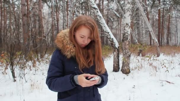 在冬季树林中着手机的女孩 iwalking — 图库视频影像