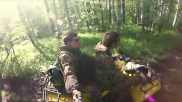 Два парня на квадроцикле едут через лес — стоковое видео