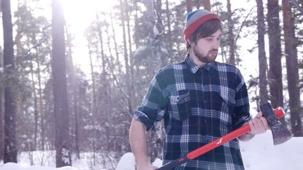 Lumberjack se para y agudiza su hacha en el bosque, fugas ligeras lo rodean — Vídeos de Stock