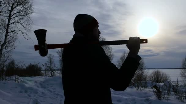 Silhouette Lumberjack de pie con su hacha al atardecer — Vídeos de Stock