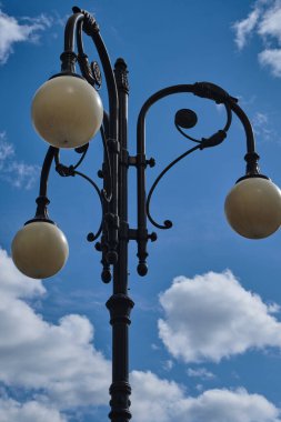 Açık hava bulutlu mavi bir gökyüzünün arka planında, yalnız bir fener var. Bir sütunda, karanlık çöktüğünde parlayan üç beyaz top var..