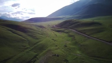 Tepeler ve destansı güzelliklerle dolu bir arabayı takip eden bir dron.