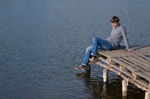 Hombre sentado en el muelle de un lago — Foto de Stock