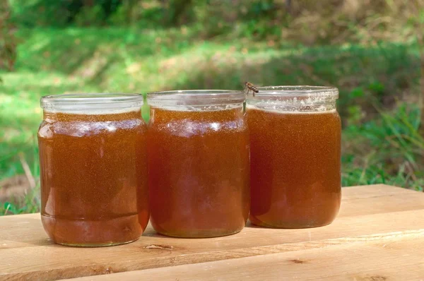 Fresh honey in glass jars on wooden table. — Stock Photo, Image