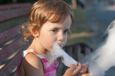 Llittle kız parkta pamuk şeker yemek