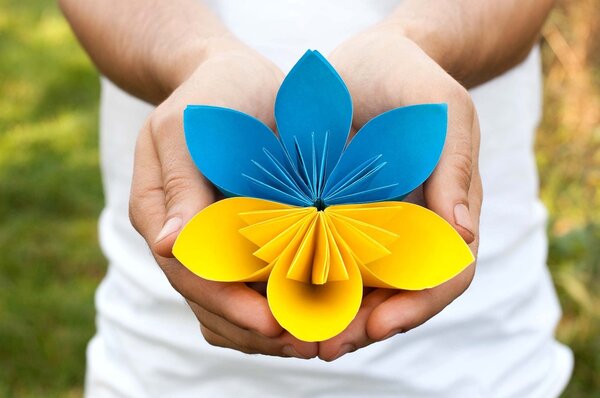 Hands holding a blue yellow paper flower