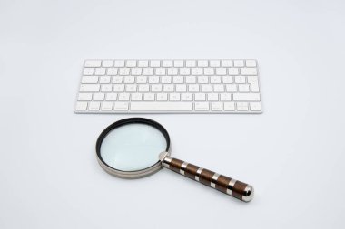 Beyaz arka planda modern klavyesi olan eski bir büyüteç.