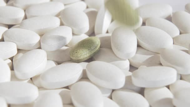 Novas pílulas verdes naturais estão caindo em cima de medicamentos químicos brancos comuns. Um símbolo da nova biomedicina e novos medicamentos naturais. Uma grande receita do médico. Novas pílulas com cannabis. — Vídeo de Stock