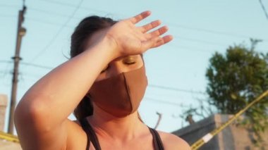 Maskeli melez bir sporcu sıkı bir çalışmadan sonra alnından teri siler. Gün batımında güçlü bir kızın yakın çekimi beton bir stadyumun arka planında. Salgın zamanında spor