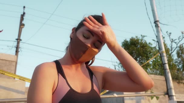 혼합 된 경주 선수가 그녀의 이마에서 땀을 닦고, 힘든 운동 끝에 신선 한 공기를 마시기 위해 마스크를 벗는다. 석양 빛을 받으며 경기장의 배경에 나타나는 강한 소녀의 근접 사진. — 비디오