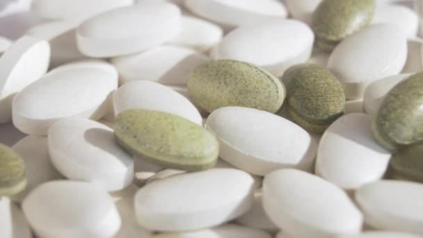 Op de roterende witte beursstand staan witte tabletten en groene natuurlijke tabletten van de nieuwe generatie. Bio vitaminen en om de immuniteit te verhogen tijdens het coronavirus. Groene pillen gemaakt van kruiden. — Stockvideo