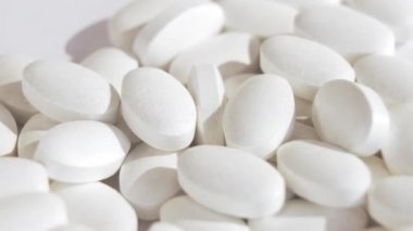 Fabrikada yeni beyaz vitamin tabletleri üretiliyor. Beyaz haplar aynı ilaçlarla dönen bir platforma düşer. Tüm bunlar parlak ışık ve zıt gölgelerin içinde. Makro.