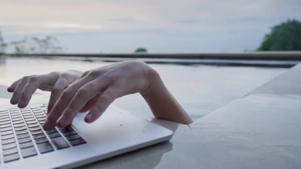 A strange close-up of a mans hands sticking out of the pool and typing on a laptop keyboard. A man on vacation in the pool is tired of work, but his hands continue to print. Slow motion. — Stock Video