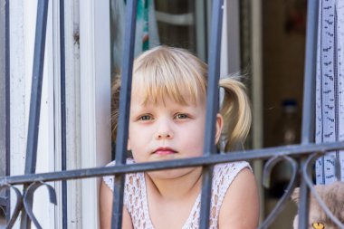 sad little girl is 4 years old, peeking behind bars clipart