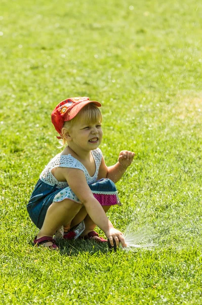 Little girl holding during irrigation, spray — Stock Photo, Image