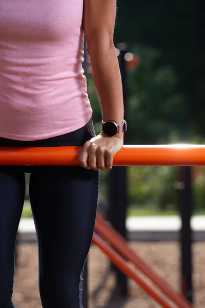 Woman at outdoor sport playground. Young woman doing gymnastic exercises at outdoor gym. Healthy active lady in summer park