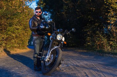 bir adam bir motosiklet ile sakal ve gözlük yolda